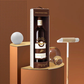 A bottle of Beluga Allure Vodka 700ml in a box is displayed on a geometric brown and gold set with a croquet mallet, white ball, and clear sphere nearby, all against a perforated brown background—evoking delicate spice and honeyed sweetness.