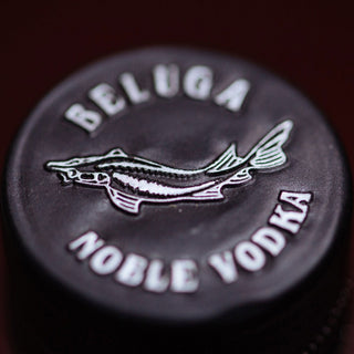 Close-up of a bottle cap with an embossed fish logo and BELUGA NOBLE VODKA text on a dark background, showcasing the elegance of Beluga Noble Winter Limited Edition Vodka 700ml.