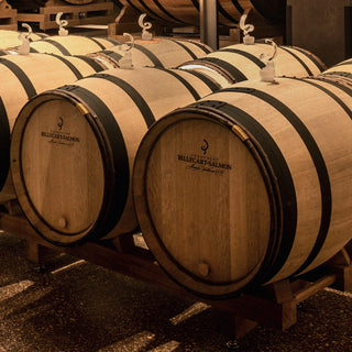 Several wooden barrels marked "Billecart-Salmon" rest on racks in a dimly lit room. Each features a white valve, evoking the elegance and craftsmanship of the Billecart-Salmon Coffret Exception Francois Duo Gift Pack.