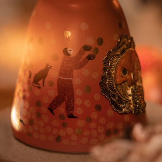 A close-up of the Clase Azul Dia de Los Muertos 2023 Aromas Limited Edition bottle, featuring a painted figure in red reaching upward with a dog nearby and a golden bearded face on the right, all amid toasted oak-inspired patterned dots.