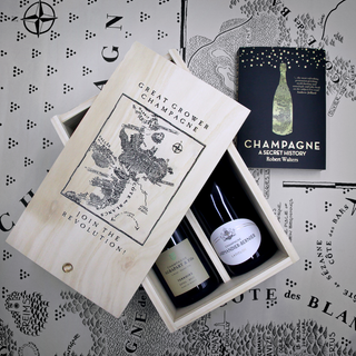 The Revolution Grower Champagne Gift Box features two mineral-driven grower Champagnes in a wooden box with a Champagne region map, plus "Champagne: A Secret History" by Robert Walters, all presented on a map-themed surface.