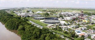 Aerial view of a coastal town with buildings and greenery along a river.