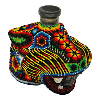 Chaquira Extra Anejo Tequila 750ml comes in a bottle shaped like an animal’s head, adorned with vibrant Huichol beadwork in red, yellow, blue, green, and black—a striking vessel for spirits with notes of roasted agave or dark caramel.