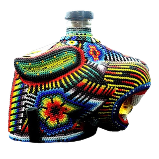 Chaquira Extra Anejo Tequila 750ml comes in a glass bottle adorned with vibrant Huichol beadwork in geometric and floral designs, hinting at the rich dark caramel and roasted agave flavors inside.