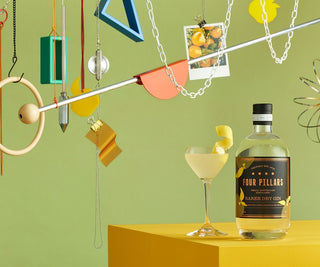 Four Pillars gin bottle with a cocktail on a yellow surface against a green background