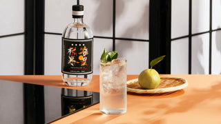 Bottle of Junmai Ginjo Sake with a glass of sake and green apple on a wooden table.
