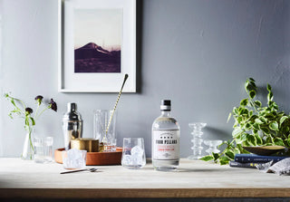 Bottle of Four Pillars gin on a bar counter with glasses and decor.