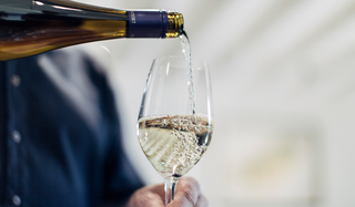 White wine being poured from a bottle into a glass with a blurred background