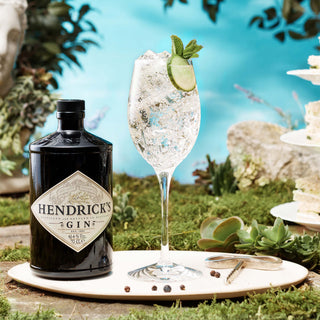 Hendrick's Gin bottle with a glass of gin and tonic on a natural background