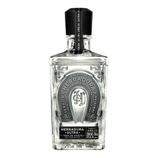 A 750ml clear glass bottle of Herradura Ultra Añejo Cristalino Tequila features a silver horseshoe emblem, black cap, and label noting 100% de agave, 40% ABV, with flavors of toasted oak and sweet agave.