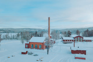 Aerial view of a snowy landscape with red buildings and a tall chimney.
