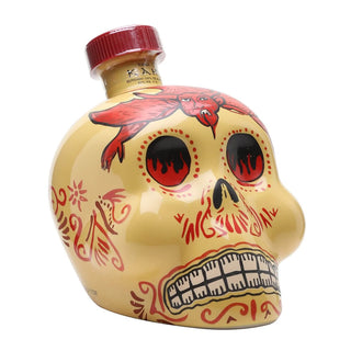 KAH Reposado Tequila 700ml comes in a beige skull-shaped bottle with bold black eye sockets, red and black designs, a devil figure on the forehead, stylized teeth, a vivid red cap, and offers hints of vanilla and cooked agave.