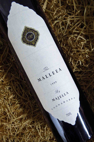 Wine bottle labeled 'The Malleea 1999 by Majella Coonawarra' on a straw background