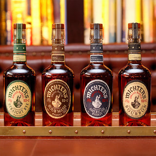 A bottle of Michter’s US*1 American Whiskey sits on a polished wooden bar, promising a smooth finish with hints of vanilla and caramel.