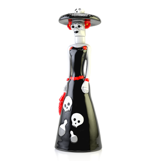 Doña Celia Reposado Tequila 100ml comes in a ceramic figurine of a woman in a black dress with white skulls, a wide skull-topped hat, red accents, and a red handbag—an artful bottle with vanilla and caramel tones.
