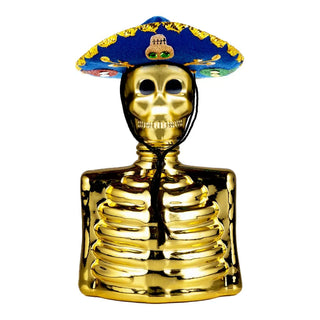 The Los Azulejos Skelly Anejo Tequila Gold Edition 750ml features a shiny gold skeleton torso with a grinning skull, wearing a vibrant blue sombrero adorned with yellow trim and embroidery, embodying the lively spirit of agave.