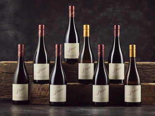 Collection of wine bottles on a wooden barrel with a dark background